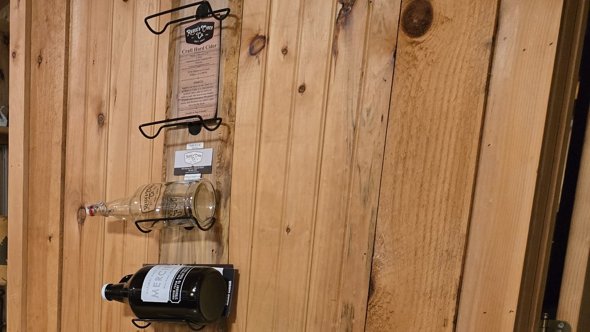 Reece's Cider and Mercier cider bottles on a cabin wall rack in North Georgia